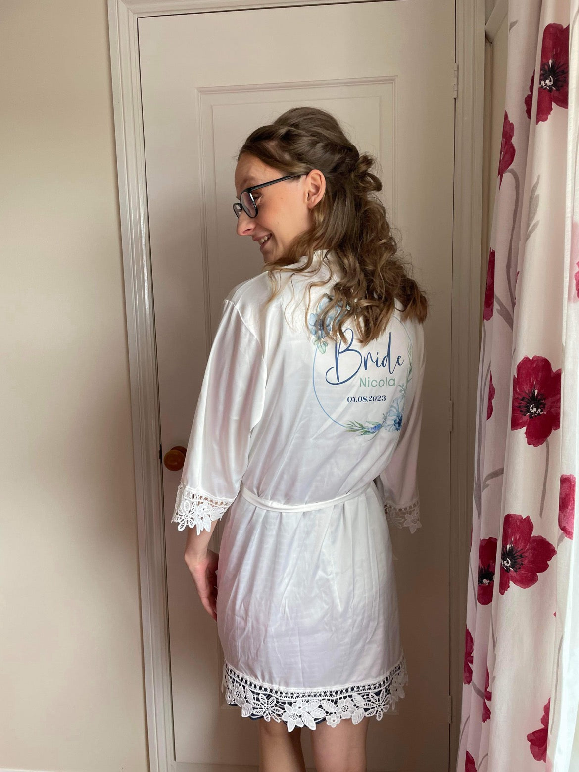 Bridal robe being worn. White robe with white lace trim and blue floral design on the back personalised with name and wedding date.
